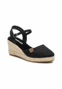 Espadrille noire à talon compensé avec un design perforé, semelle en jute, bride de cheville et petit logo. Tissu texturé et finition lisse.