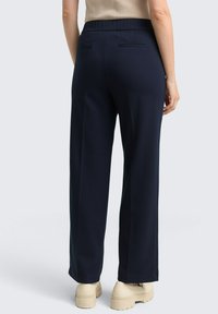 Granatowe spodnie szerokie w nogawkach z elastycznym paskiem w talii, gładką teksturą, dwoma tylnymi kieszeniami i dopasowanym krojem.
