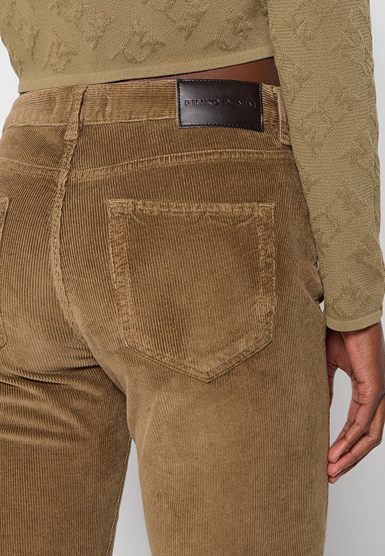 Brązowe spodnie w korduroy z teksturowym wykończeniem, posiadające dwie tylne kieszenie oraz skórzaną metkę na pasku z wytłoczonym logotypem.