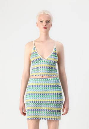 Ensemble en tricot comprenant un bralette et une mini jupe. Motif bleu, vert, jaune et violet avec des bords festonnés et des bretelles fines.