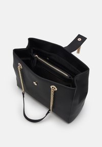 Svart tote-väska gjord av texturerad konstläder med guldfärgad metall. Innehåller dubbla kedje- och remhandtag samt ett inre dragkedjefack.