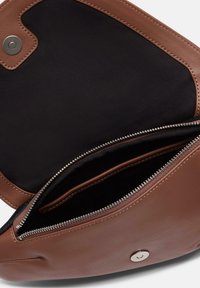 Braune Lederhandtasche mit einem schwarzen Stoffinneren, ausgestattet mit einer Reißverschlusstasche und einem Druckknopfverschluss. Glatte Textur mit sichtbaren Steppdetails.