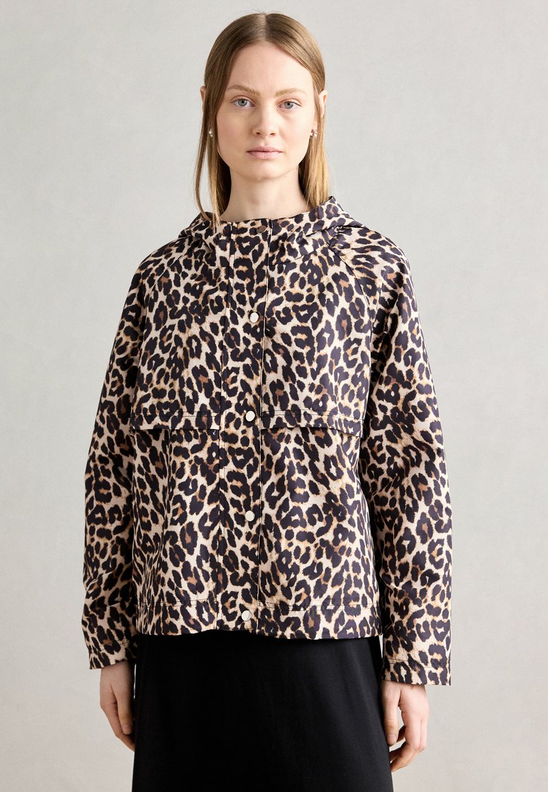 Jachetă cu imprimeu de leopard, cu glugă, având un sistem de închidere cu nasturi, mâneci raglan și o croială lejeră. Fabricată dintr-un material ușor și neted.