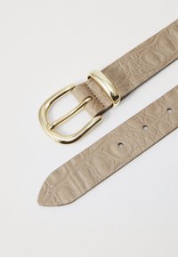 Beige leather belt with a textured pattern, featuring a gold-tone metal buckle and multiple adjustment holes near the tapered end.