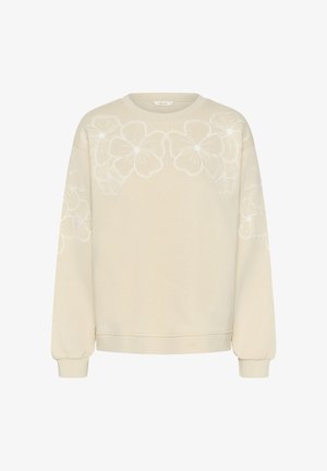 Jasnobeżowa bluza z białym kwiatowym haftem na przodzie, okrągłym dekoltem i długimi, lekko marszczonymi rękawami.