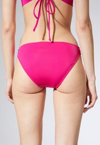 Różowy dół bikini o gładkiej teksturze, średnim kroju i minimalnym kryciu. Posiada czyste szwy oraz bezszwowy pas dla wygody.