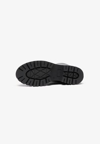 Semelle de botte en caoutchouc noir avec des crampons profonds et un motif texturé, dotée d'un bout arrondi et d'une construction durable et robuste.