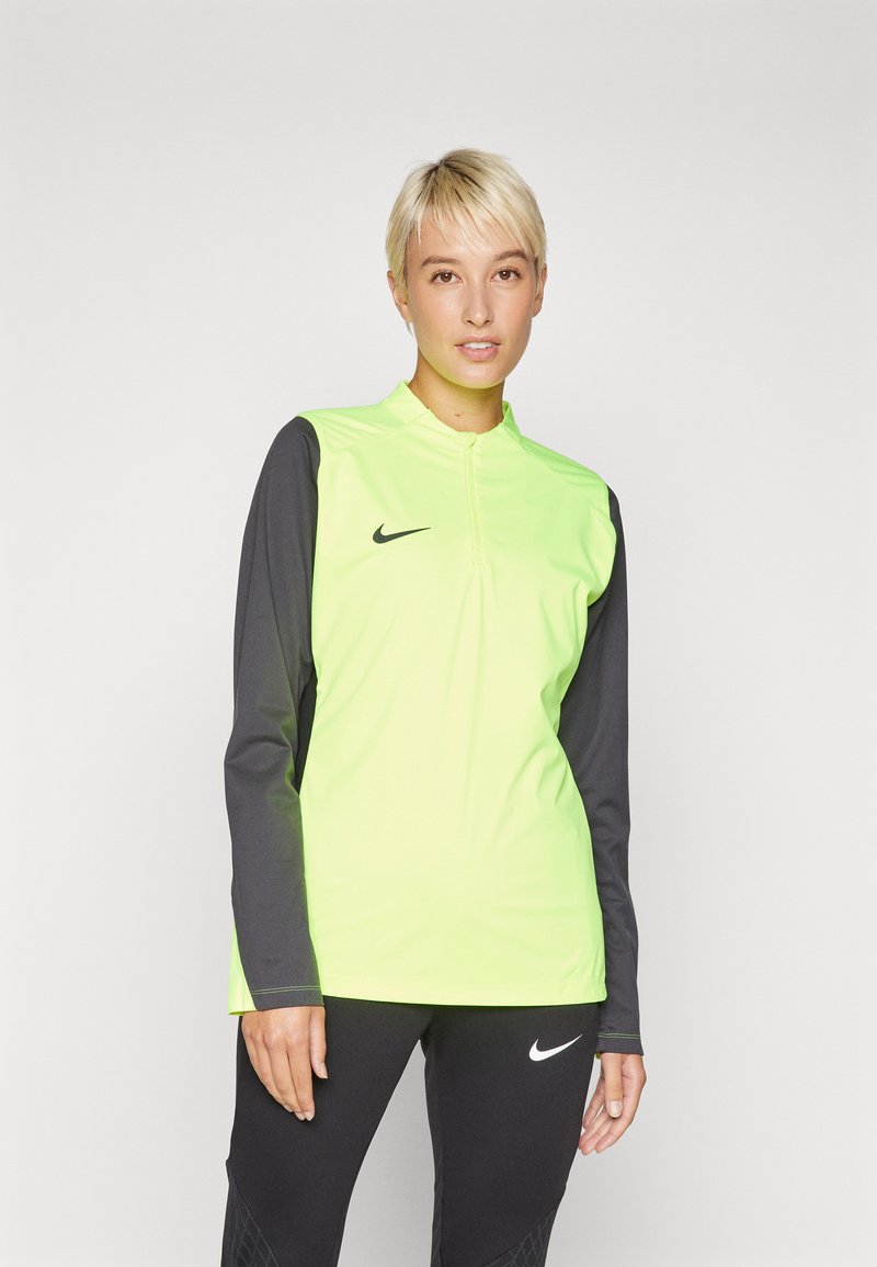 Nike majica dugih rukava s prednjim dijelom u svijetloj žutozelenoj boji i tamnosivim rukavima, s vratom na četvrtinu zatvarača i crnim logotipom.