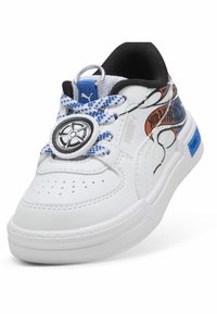 Białe sneakersy z czarnymi akcentami, z niebieskimi sznurowadłami i dekoracyjnym motywem kółek. Zaprojektowane z perforacjami dla lepszej wentylacji.