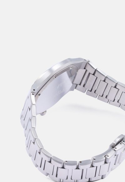 Orologio da polso in metallo silver con cassa rettangolare e bracciale a maglie. La superficie è spazzolata e lucidata, con quadrante numerico.