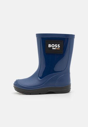 Botte de pluie en caoutchouc bleu avec une finition brillante, étiquette noire portant "BOSS", et une semelle noire texturée pour une meilleure adhérence. Design de hauteur mi-mollet.