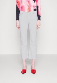 Harmaat lyhyet housut suoran lahkeen leikkauksella, yhdistettyinä punaisiin avokasokenkiin. Kangas näyttää sileältä ja siinä on hienoinen kiilto.