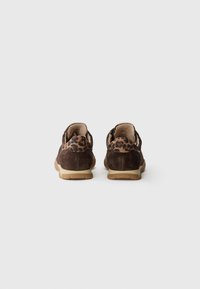 Chaussures en daim marron avec détail de motif léopard sur le talon, semelles beiges, présentées de dos sur un fond blanc uni.