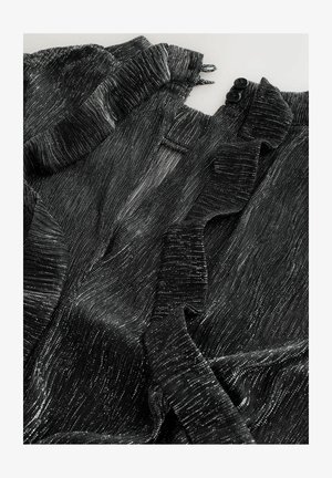 Čierna textúrovaná tkanina s kovovými striebornými vláknami; má volánové okraje a dve čierne gombíky na výstrihu.