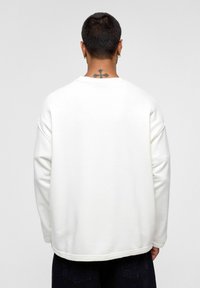 Witte pullover sweatshirt met een ronde hals en verlaagde schouders. Beschikt over een zachte, gestructureerde stof en een rechte zoom.