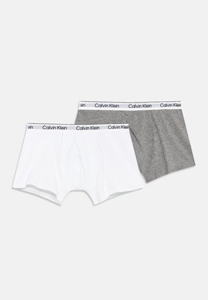 Két pár Calvin Klein boxeralsó, egy fehér és egy szürke, márkázott elasztikus derékpánttal, egyszínű háttéren.