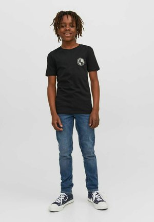Black cotton t-shirt with a round neckline and short sleeves, featuring a graphic print on the left chest. Worn with blue jeans and sneakers.