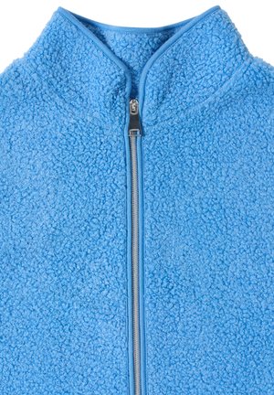 Veste polaire bleu clair avec une fermeture éclair argentée et un col montant, montrant une surface de tissu texturée et bouclée.