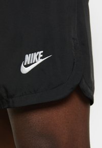 Svarta sportshorts med en slät textur, med en vit broderad Nike-logotyp vid fållen. Enkelt mönster utan några ytterligare dekorationer.