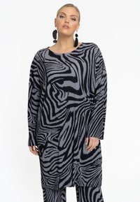 Zwart en grijs gestreepte tuniek van ribbelstof, met een comfortabele pasvorm, lange mouwen en een ronde halslijn, gedragen met bijpassende broek.