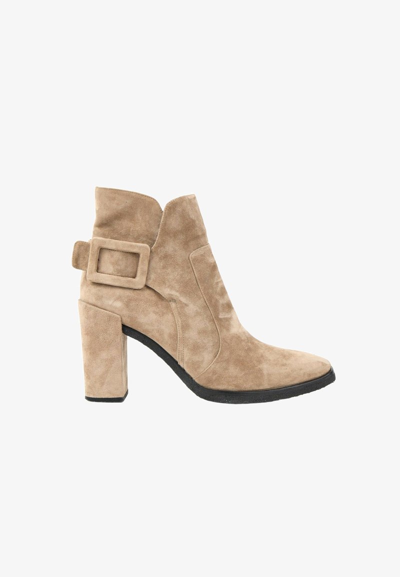 Bottine beige en daim avec un talon haut et épais, un bout pointu et une grande boucle carrée sur le côté.