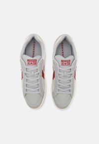 Tenis gri cu logo roșu în formă de stea, șireturi plate, guler căptușit, zonă perforată la vârful pantofului și talpă intermediară; talpă din cauciuc pentru aderență și durabilitate.