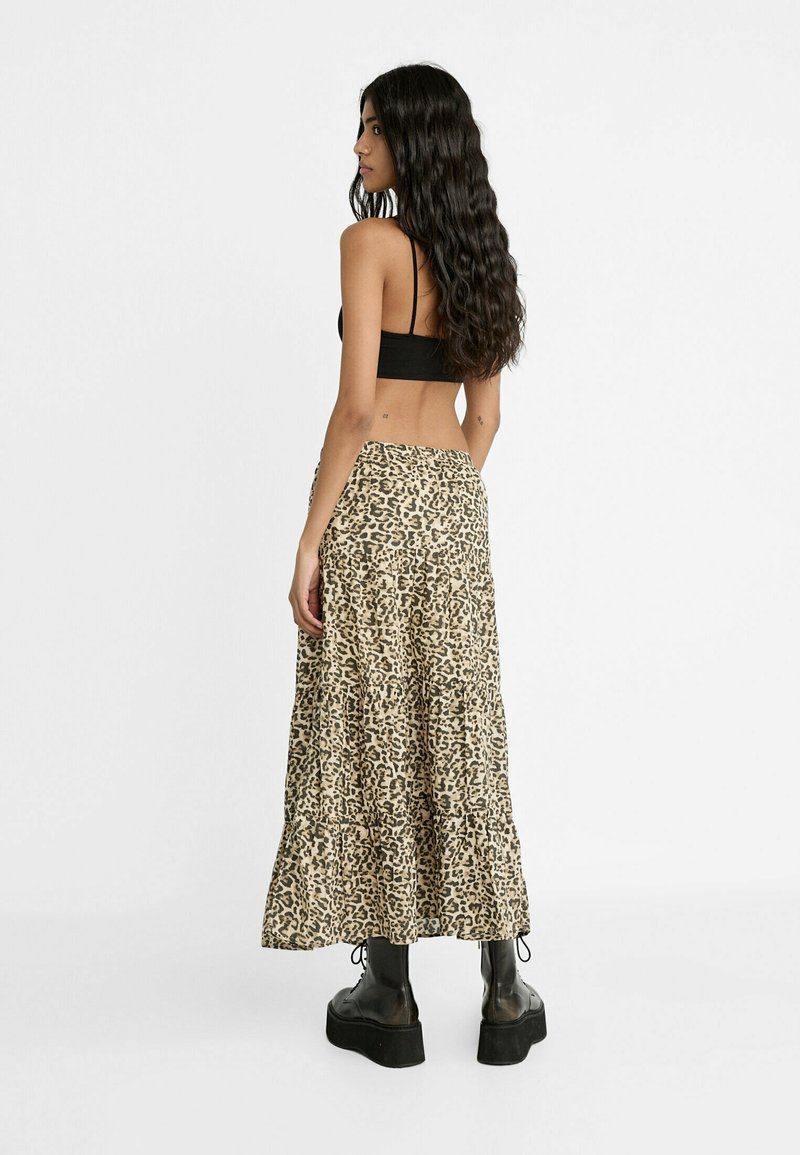 Maxi-rock im Leopardenmuster in Beige mit gerafften Lagen, kombiniert mit einem schwarzen cropped Top. Klobige schwarze Plateaustiefel runden den Look ab.