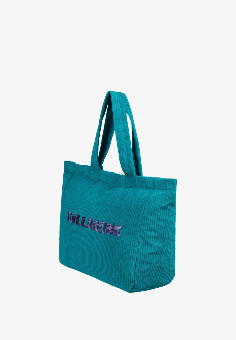 Turkusowa torba tote z korduroy z dwiema materiałowymi uchwytami oraz haftem "Billabong" w kolorze fioletowym i różowym. Teksturowana powierzchnia z prążkowanym wzorem.