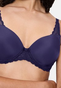 Laivastonsininen rintaliivit, joissa on sileät kupit, pitsireunus reunoilla ja pieni satiininauha keskellä edessä. Säädettävät olkaimet istuvuuden varmistamiseksi.