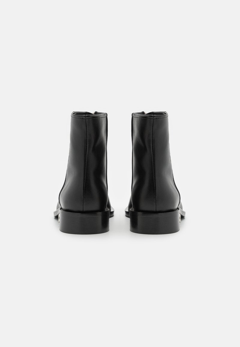 Schwarze Leder-Stiefeletten mit glatter Textur, runder Zehenpartie und niedrigem, klobigen Absatz. Nahtdetails verlaufen vertikal entlang der Rückseite.