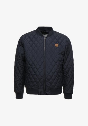 Quiltelt tengerészkék bomber dzseki bordázott mandzsettákkal és derékkal, elülső cipzárral és egy kis bőrből készült logójal a bal mellrészen.