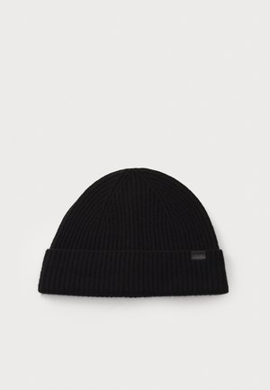 Black ribbed knit beanie with a folded cuff and a small rectangular label on the side. Soft texture, rounded top, and simple design.