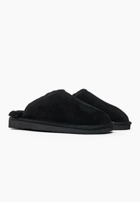 Mustat samettisat tossut, joissa on pehmeä vuori, pyöristetty kärki ja liukuvasti päältä pantava muotoilu, jonka pohjassa on teksturoitu musta kumi.