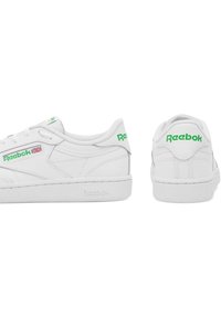 Valged nahast tossud rohelise Reebok logo'ga. Madal disain, ümar varvas, tekstureeritud kummikreen ja nähtavad õmblustega detailid.