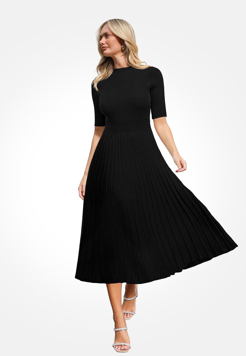 Zwarte jurk tot op de knie met een ribgebreid lijfje en een geplisseerde rok, gemaakt van een gestructureerde stof. Korte mouwen en een aansluitende taille accentueren de vorm.