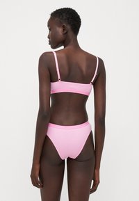 Roze bikini set met een strakke bralette met verstelbare bandjes en een hooggesneden broekje, gemaakt van gladde, rekbare stof.