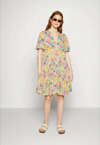 Vestido florido com decote em V, mangas curtas e soltas, cores vibrantes incluindo rosa, amarelo e azul, e uma silhueta fluida em A.