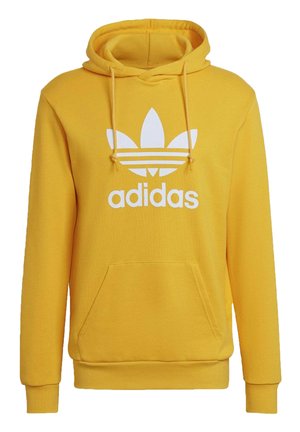 Sweat à capuche jaune Adidas avec logo trèfle blanc et texte sur le devant, poche kangourou avant et capuche à cordon réglable.