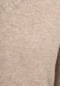 Beige gestrickter Pullover mit V-Ausschnitt, der eine weiche Textur und ein dezentes gesprenkeltes Muster aufweist, ideal für die Freizeit.