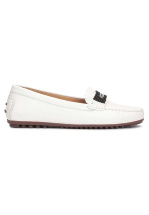Valkoinen nahkainen loafer, jossa ruskea kumipohja nastoilla ja musta kangasbandi päällä, näytetty sivuprofiilissa.