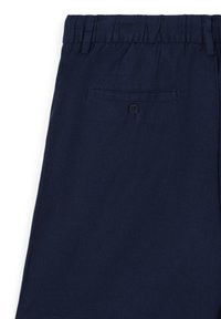 Pantalon en coton bleu marine avec une taille élastique, présentant une poche arrière unique avec fermoir à bouton et une texture lisse et mate.