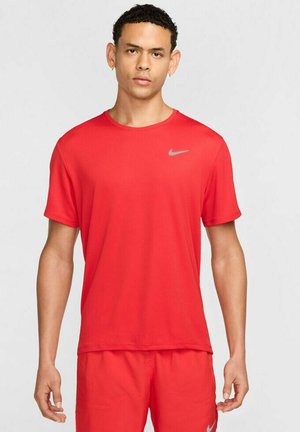 Camiseta atlética roja de Nike, de mangas cortas, con tejido suave, cuello redondo, presenta un pequeño logo gris en el pecho, diseño ligero y ajustado.