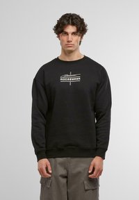 Sudadera negra con cuello redondo, mangas largas y puños acanalados. Presenta un diseño de logo frontal en blanco, fabricada con una mezcla de algodón.