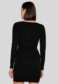 Abito bodycon nero con maniche lunghe, caratterizzato da un motivo testurizzato. I dettagli includono un colletto rotondo e una chiusura con zip sul retro.