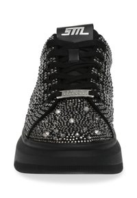 Sneaker nera con embellimenti di borchie, tessuto testurizzato, punta arrotondata, suola spessa nera e logo sulla linguetta. I lacci sono disposti centralmente.