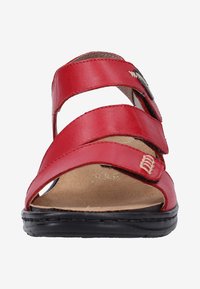 Sandale en cuir rouge avec trois sangles réglables, bout ouvert et semelle noire texturée. Présente une semelle intérieure beige et des coutures décoratives.