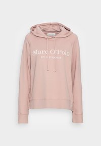 Sudadera con capucha de color rosa claro con un ajuste holgado, que incluye un bolsillo canguro, cordones y una marca de texto blanca en la parte frontal.