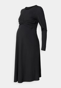 Vestido de maternidad negro de manga larga con detalle de tela fruncida sobre la barriga y falda acampanada.