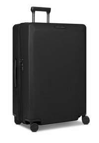 Valigia rigida nera con superficie testurizzata, doppie ruote, manico retrattile e chiusura con cerniera. Marchio discreto sul pannello anteriore.