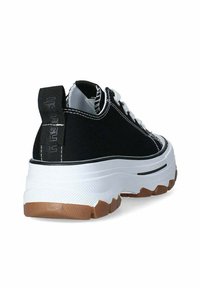 Zapatillas de lona negras con suela gruesa blanca y suela de goma marrón. Presentan costuras blancas y una pestaña negra en el talón.